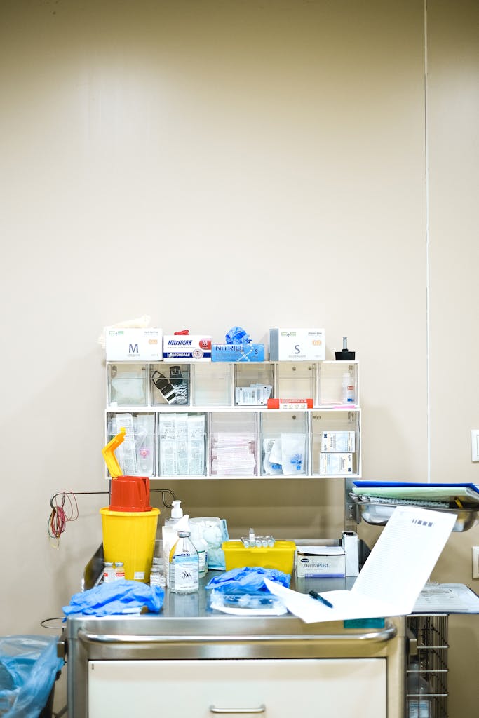 Neatly arranged medical supplies on a shelf in a hospital setting, featuring gloves, containers, and paperwork.