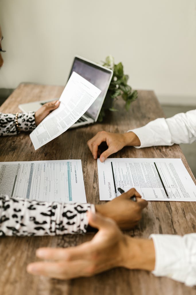 Two people reviewing documents at a wooden table during a business meeting.